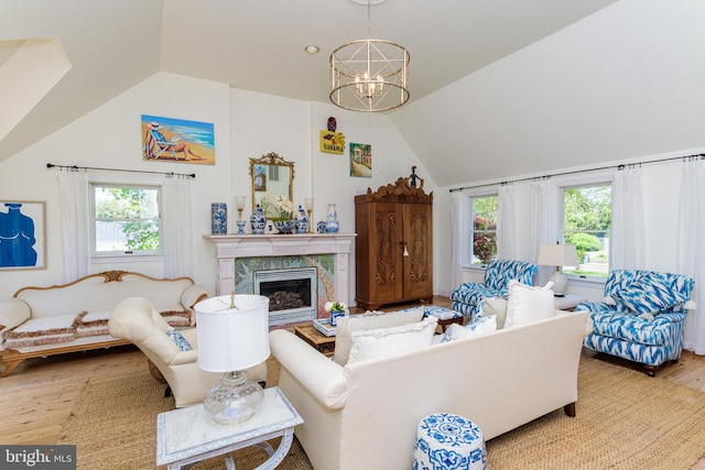 living room with a notable chandelier, plenty of natural light, hardwood / wood-style flooring, and a high end fireplace