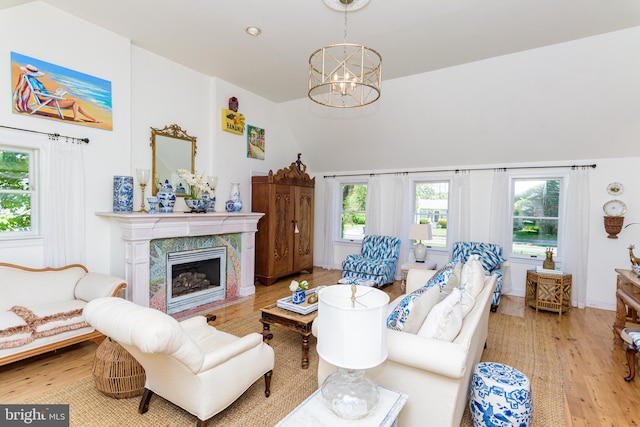 living room with an inviting chandelier, light wood-type flooring, and a premium fireplace