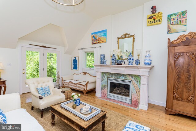 living room with lofted ceiling, light hardwood / wood-style floors, and a premium fireplace