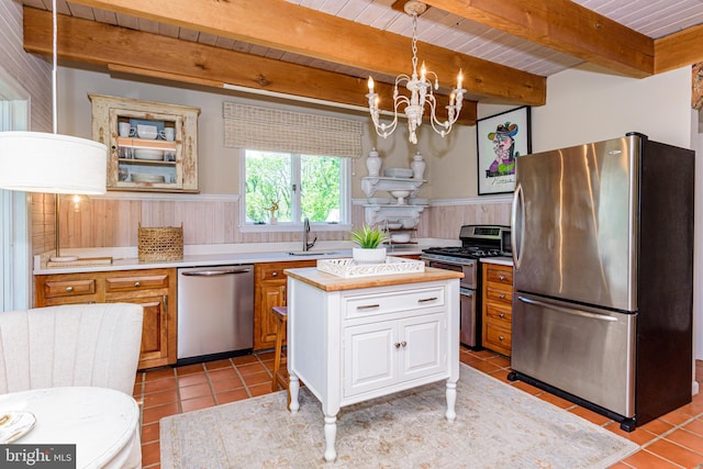 kitchen featuring a center island, appliances with stainless steel finishes, beamed ceiling, and light tile floors