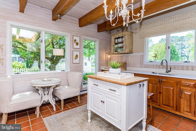 kitchen with decorative light fixtures, beamed ceiling, sink, a chandelier, and dark tile floors