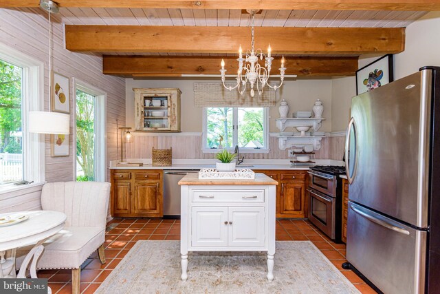 kitchen featuring a kitchen island, a healthy amount of sunlight, appliances with stainless steel finishes, and beamed ceiling