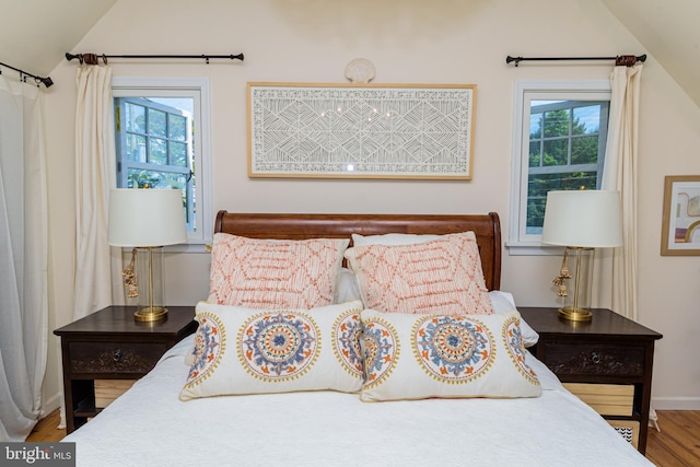 bedroom featuring lofted ceiling, hardwood / wood-style floors, and multiple windows