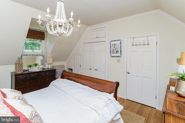 bedroom with crown molding, lofted ceiling, hardwood / wood-style flooring, a closet, and a chandelier