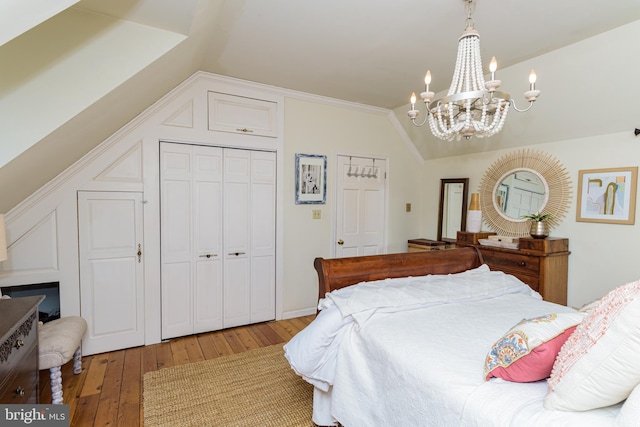 bedroom with a chandelier, vaulted ceiling, and hardwood / wood-style floors