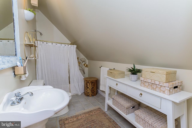 bathroom with vaulted ceiling, tile flooring, and sink