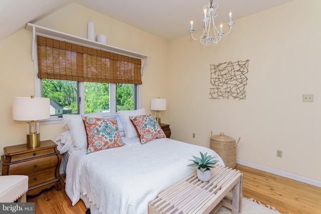 bedroom with wood-type flooring, a notable chandelier, and lofted ceiling