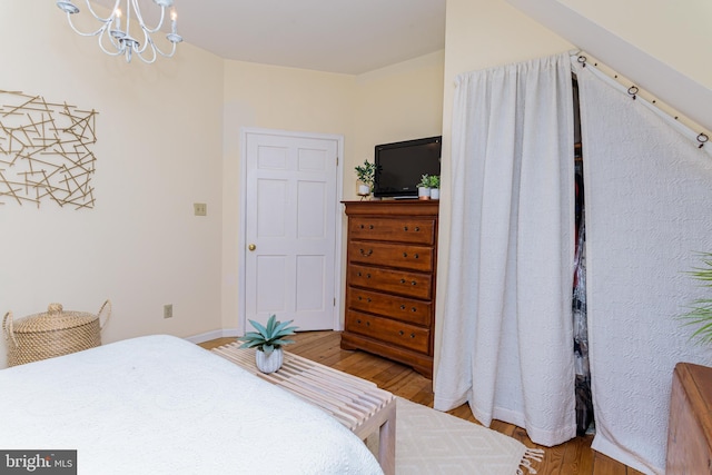 bedroom with hardwood / wood-style floors and an inviting chandelier