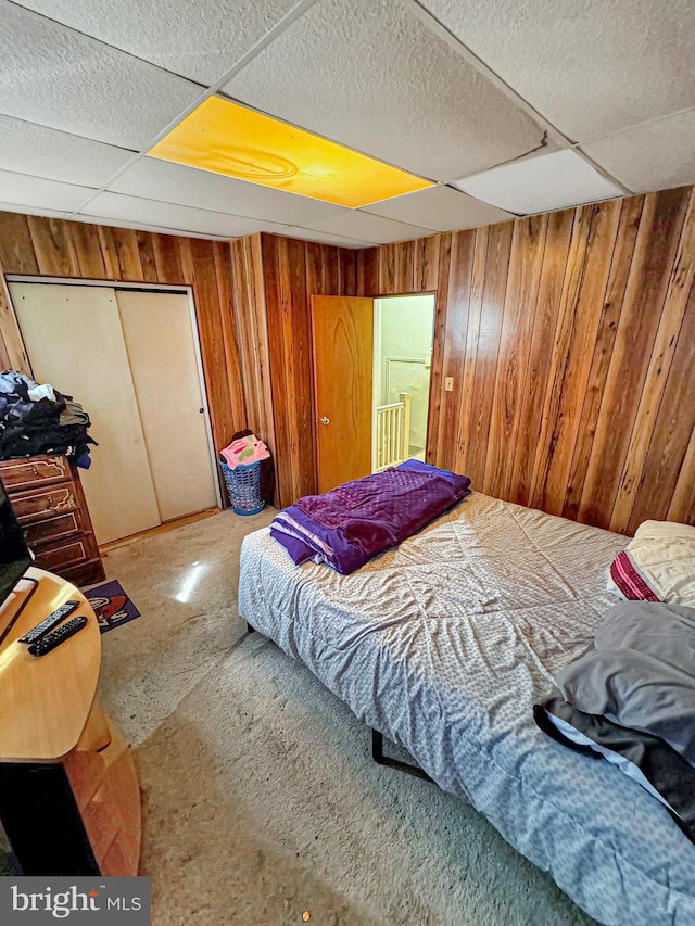 bedroom with wood walls and a paneled ceiling