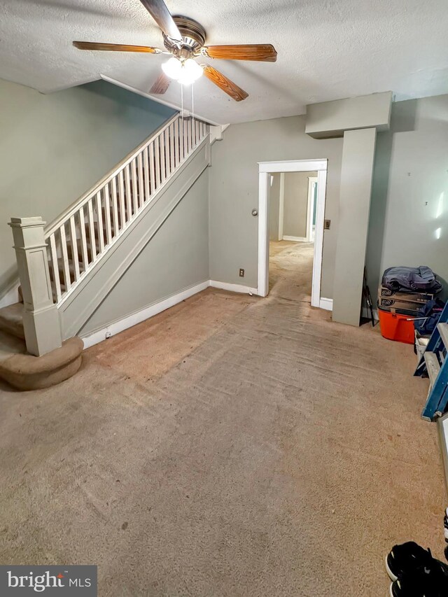 interior space with a textured ceiling, carpet, and ceiling fan