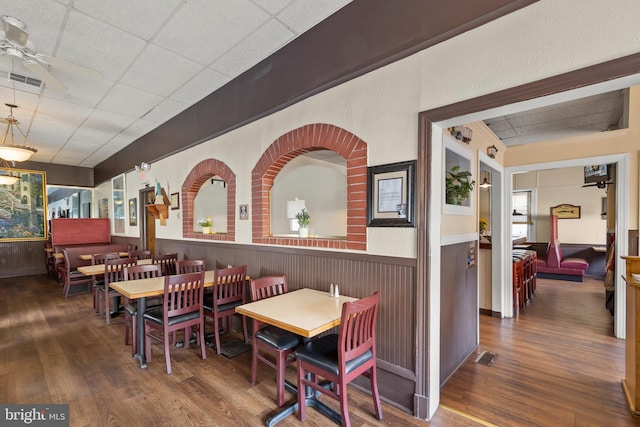 dining area featuring dark hardwood / wood-style floors, a drop ceiling, and ceiling fan