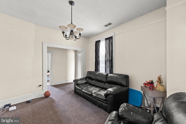 living room with a textured ceiling, a notable chandelier, and dark colored carpet