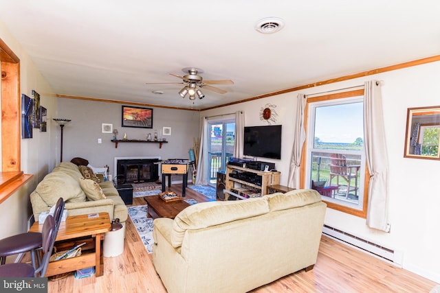 living room with a wealth of natural light, ceiling fan, light wood-type flooring, and a baseboard heating unit