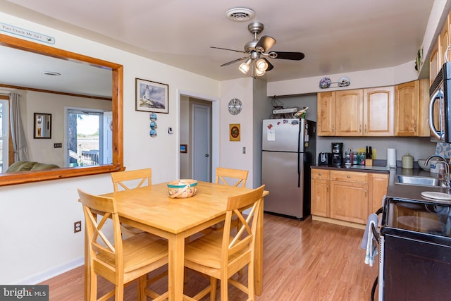 dining room featuring ceiling fan, sink, and light hardwood / wood-style floors