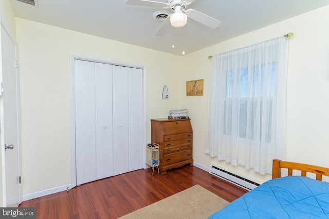 bedroom with ceiling fan, a closet, dark hardwood / wood-style floors, and a baseboard heating unit