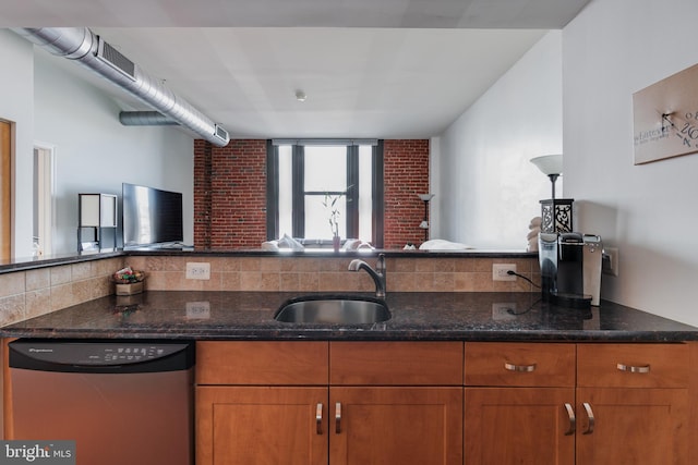 kitchen with dark stone counters, stainless steel dishwasher, sink, and backsplash