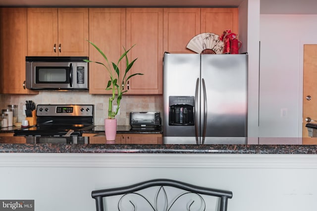 kitchen with dark stone countertops, decorative backsplash, and appliances with stainless steel finishes