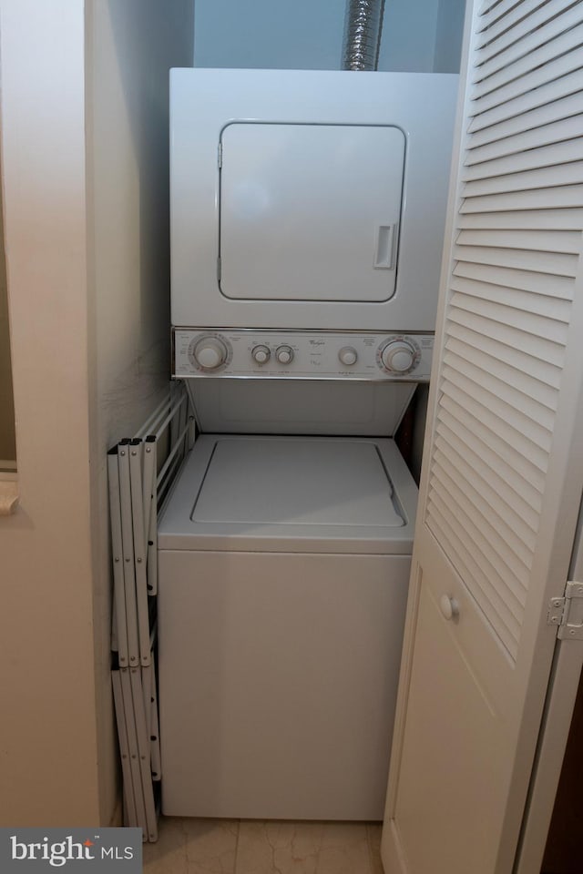 washroom featuring stacked washer and dryer and light tile patterned flooring