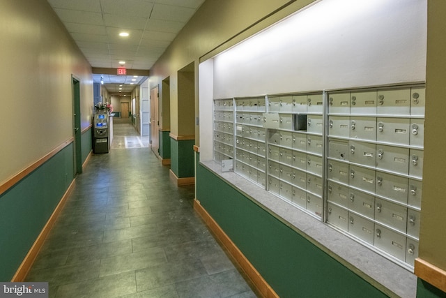 hall featuring a drop ceiling and mail boxes