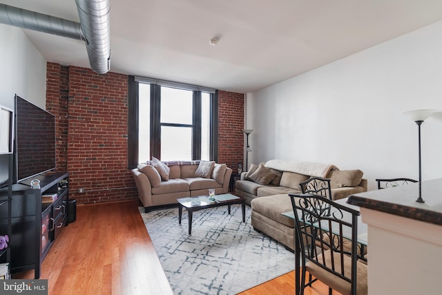 living room with light wood-type flooring and brick wall