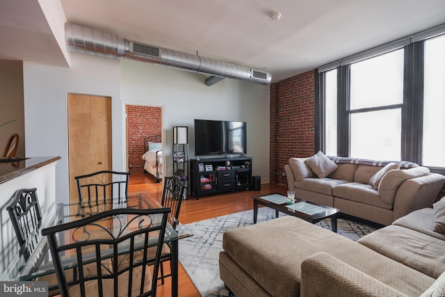 living room with light wood-type flooring and brick wall