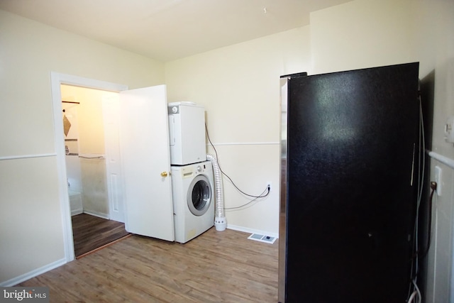 laundry area with hardwood / wood-style floors and stacked washer / dryer