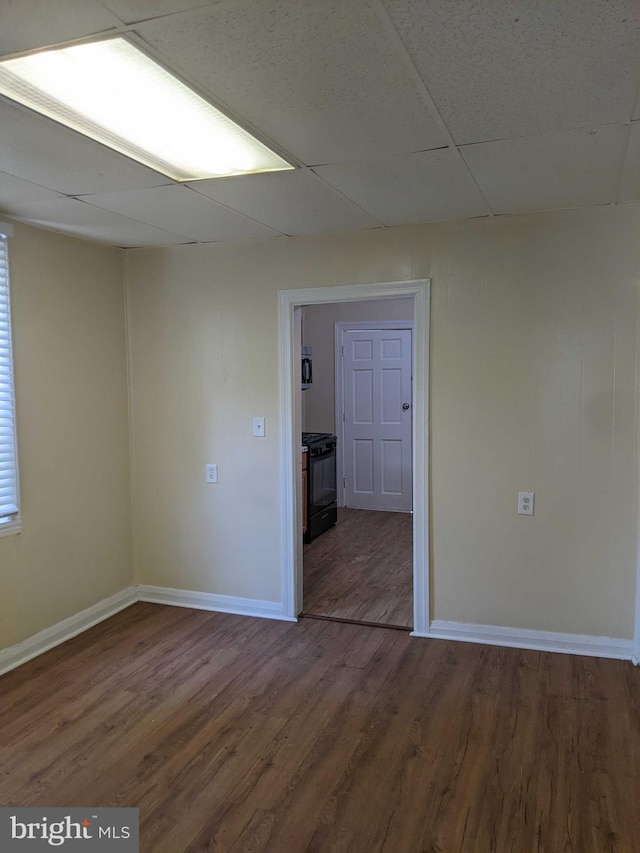 spare room with dark hardwood / wood-style flooring and a paneled ceiling