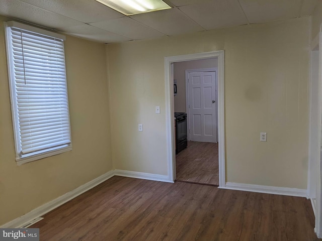 spare room with a drop ceiling, hardwood / wood-style flooring, and a wealth of natural light