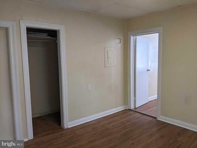 unfurnished bedroom with a closet, dark hardwood / wood-style floors, and a paneled ceiling