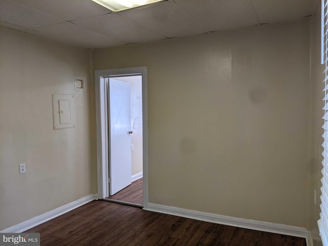 spare room featuring a drop ceiling and dark hardwood / wood-style floors