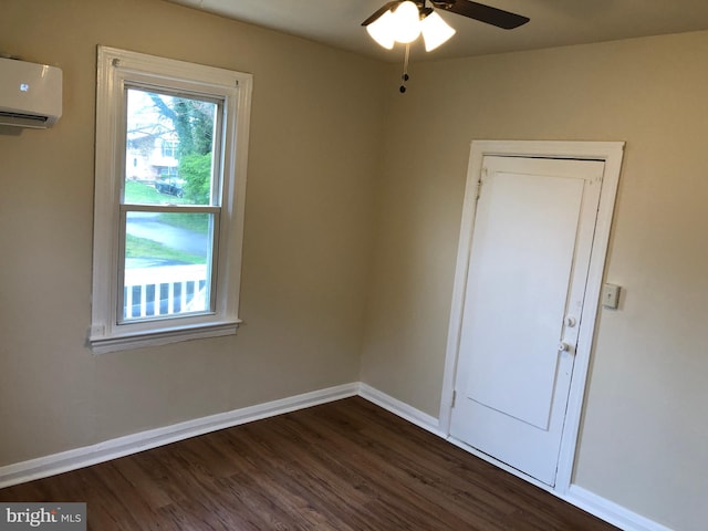 spare room with ceiling fan, dark wood-type flooring, and a wall unit AC