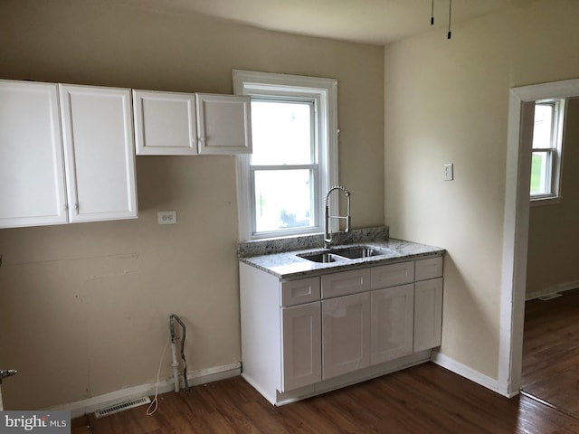 kitchen with sink, dark wood-type flooring, light stone countertops, and white cabinetry