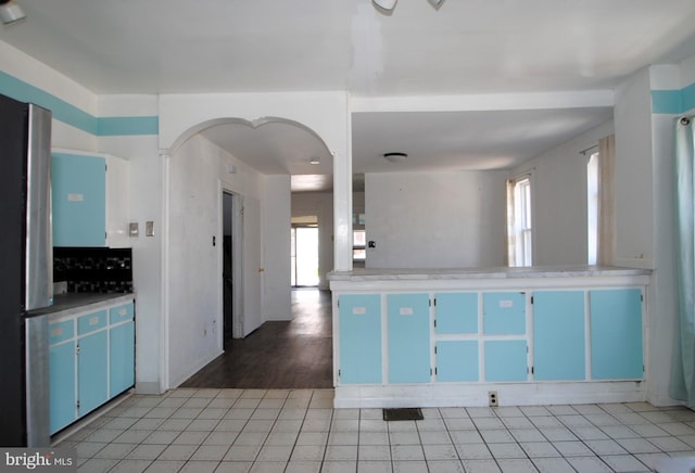 kitchen with blue cabinets, hardwood / wood-style flooring, and a healthy amount of sunlight