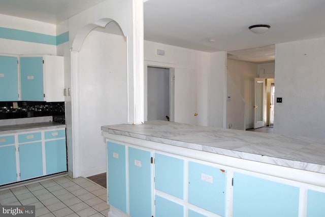 kitchen featuring blue cabinets, light tile patterned floors, and tasteful backsplash