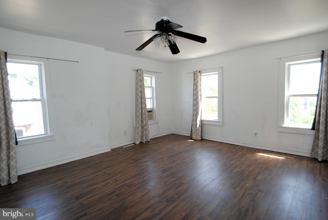 empty room featuring ceiling fan, plenty of natural light, and dark hardwood / wood-style flooring