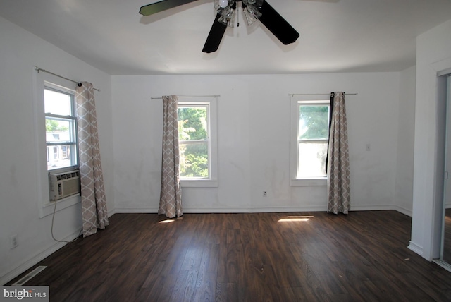 spare room featuring ceiling fan, cooling unit, dark wood-type flooring, and a wealth of natural light