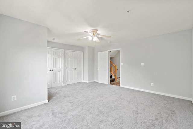 unfurnished bedroom with multiple closets, carpet floors, and ceiling fan