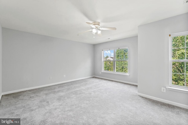 carpeted spare room featuring a wealth of natural light and ceiling fan