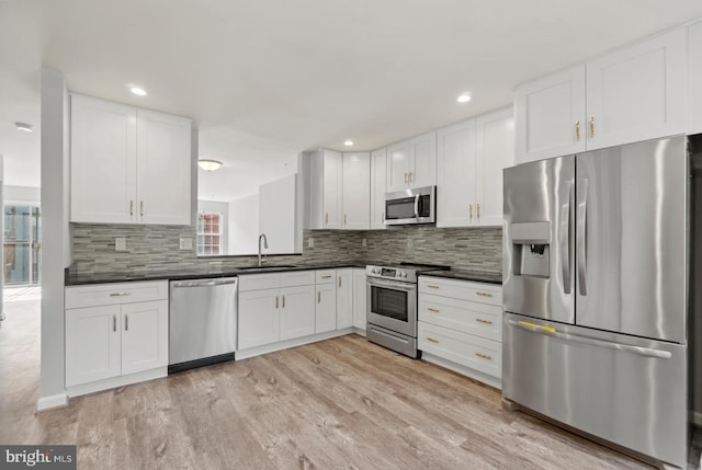 kitchen with light wood-type flooring, white cabinetry, backsplash, stainless steel appliances, and sink