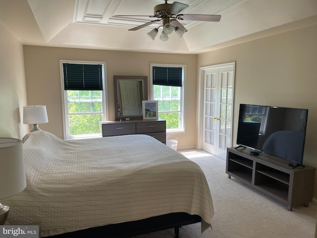 carpeted bedroom with multiple windows, ceiling fan, and a tray ceiling