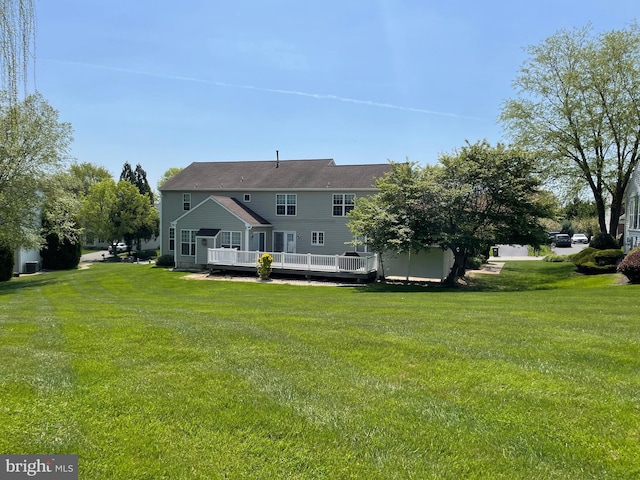 rear view of house featuring a yard and a deck