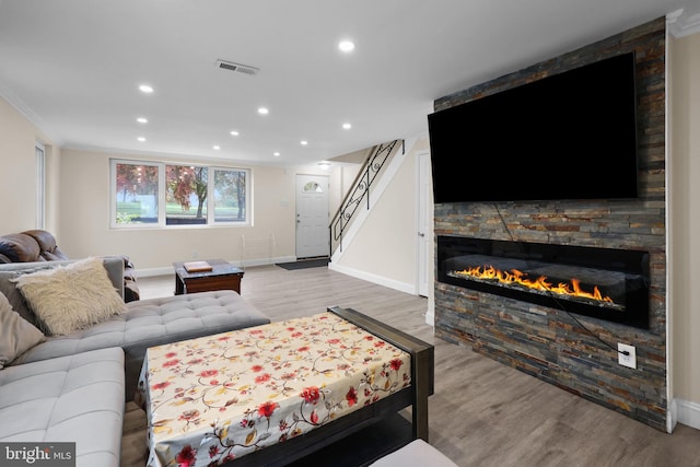 living room featuring a fireplace, ornamental molding, and light wood-type flooring