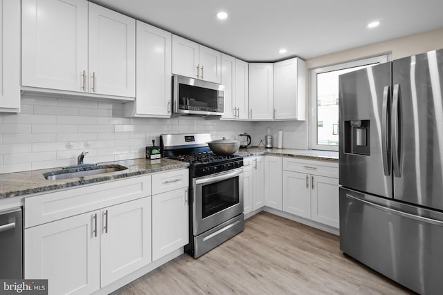 kitchen with white cabinetry, light hardwood / wood-style flooring, stainless steel appliances, and sink