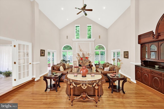 living room with high vaulted ceiling, french doors, ceiling fan, and light wood-type flooring