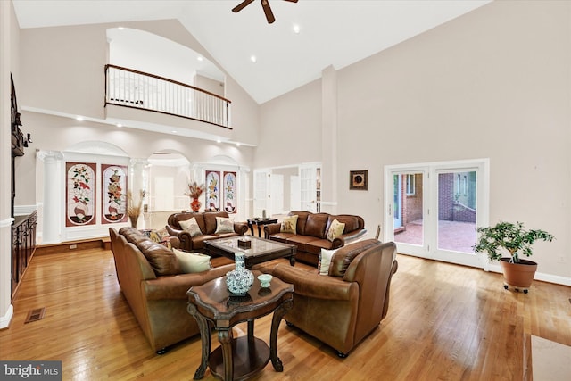 living room featuring high vaulted ceiling, ceiling fan, decorative columns, and light wood-type flooring