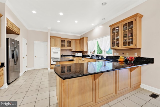 kitchen with white appliances, light tile flooring, backsplash, dark stone counters, and kitchen peninsula