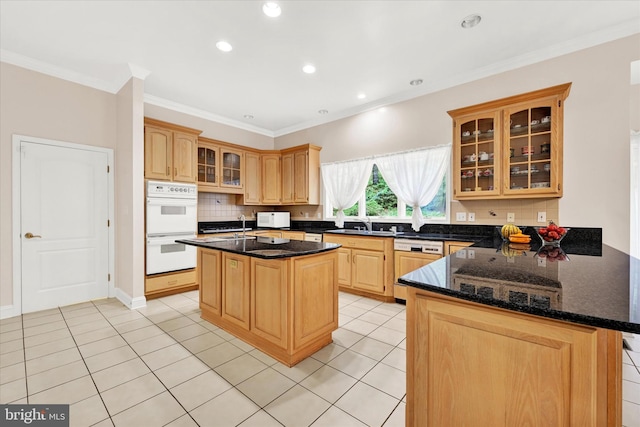 kitchen with white appliances, backsplash, dark stone counters, kitchen peninsula, and a kitchen island with sink