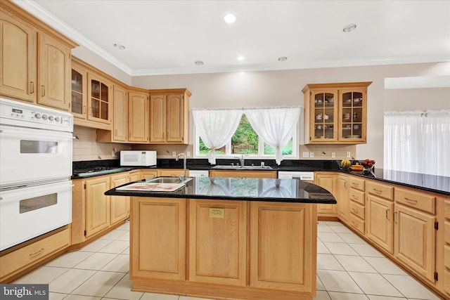 kitchen featuring white appliances, a center island with sink, and light tile floors