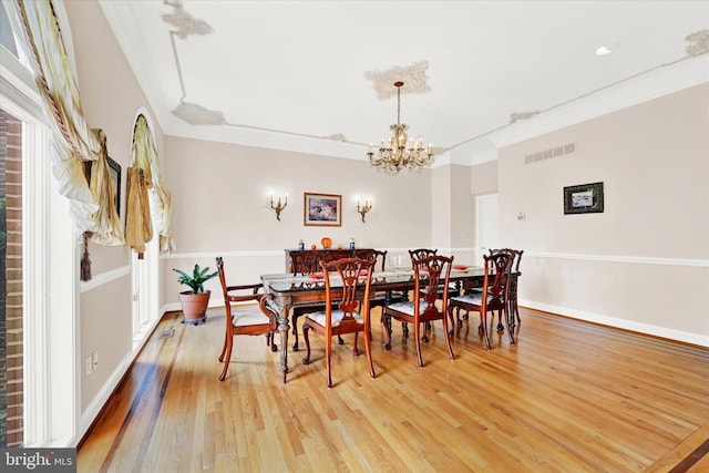 dining area featuring ornamental molding, light hardwood / wood-style floors, and a chandelier