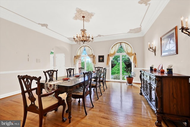 dining room featuring a notable chandelier, light hardwood / wood-style floors, crown molding, and a raised ceiling